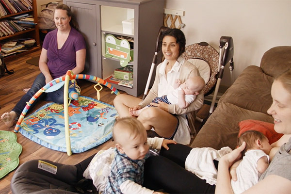 Women in living room nursing and playing with babies