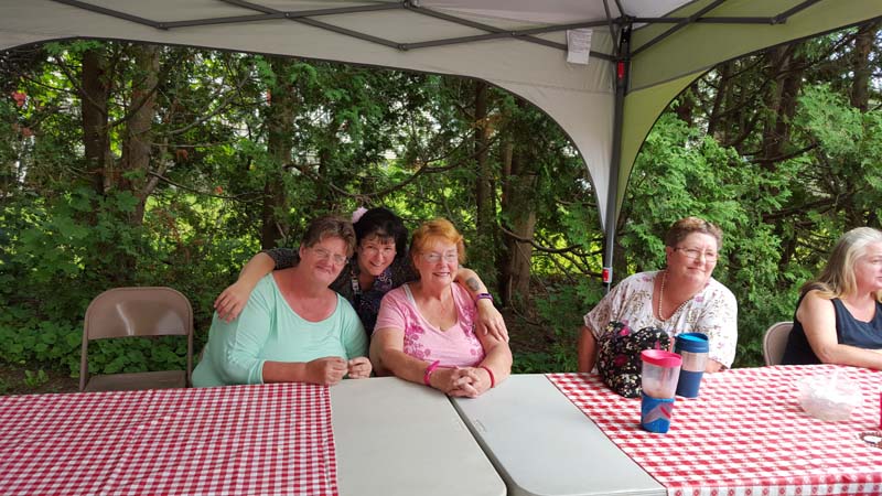 Women sitting at tables underneath a tent