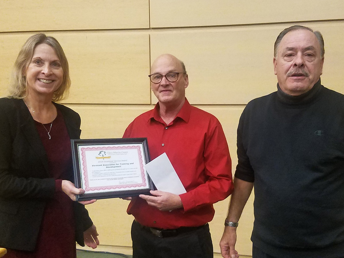 Vermont Associates for Training and Development's Rick Smedley and Pedro Baez as the recipients of the Vocational Service Award in 2018. At left is a Clara Martin Center employee presenting the award