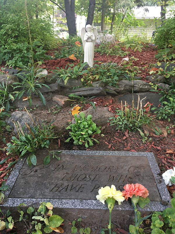 Memorial garden with angel statue, plaque, and flowers