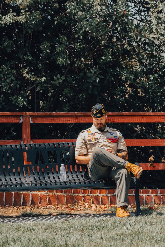 A veteran in uniform seated on a park bench in Los Angeles, reflecting outdoors.
